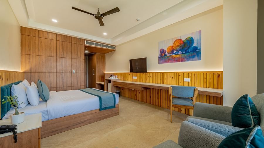 Well-lit executive king bedroom in Hotel Highway King, Bagru, with modern interiors, featuring a king size bed and wooden furnishings.