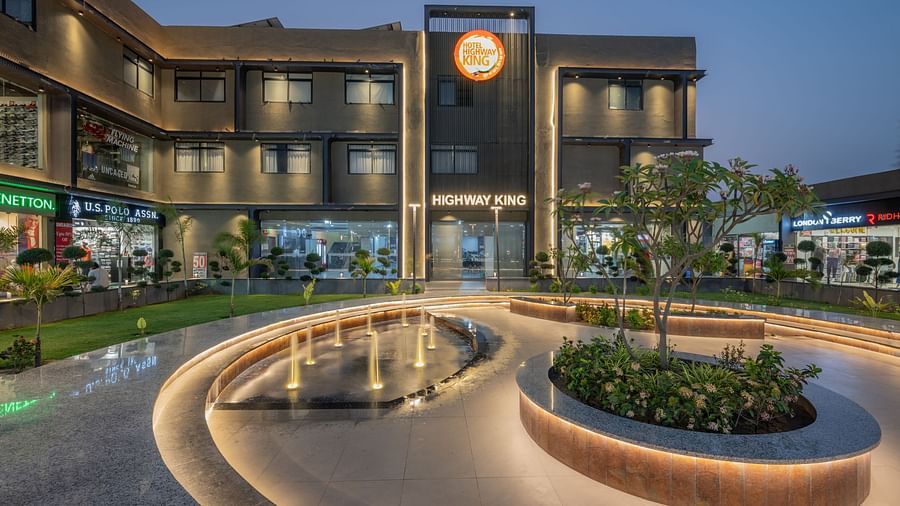 Facade and well-manicured lawn of Hotel Highway King, Behror, which also features a large illuminated logo of the property.