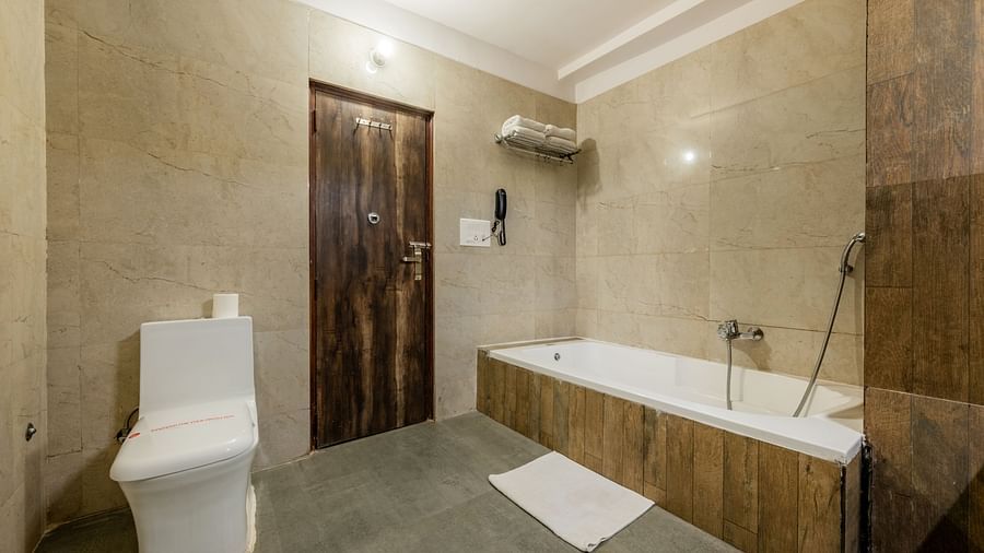 Bathtub with necessary fittings and western commode in the bathroom of the Suite in Hotel Highway King, Behror.