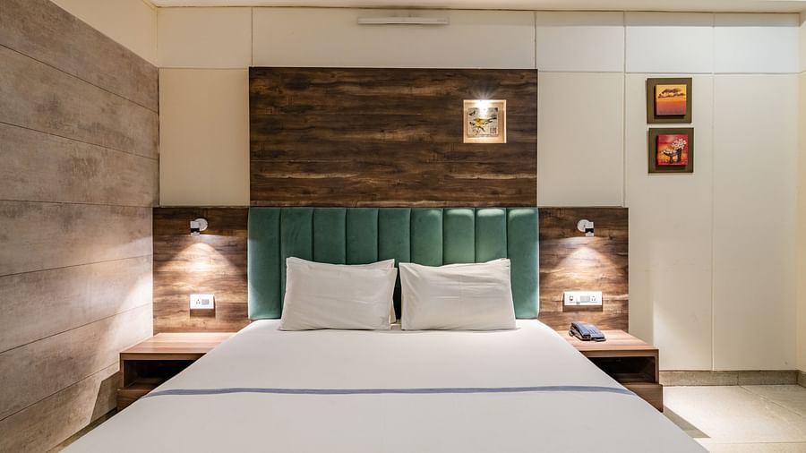 A close up of the double bed with bedside tables and ample lighting in Maharaja Deluxe Room of Hotel Highway King, Behror.