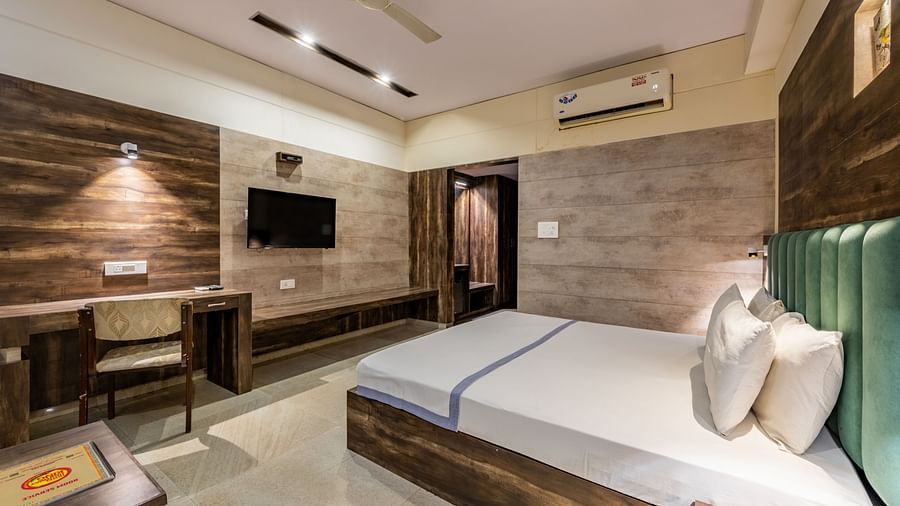 Extended view of the Maharaja Deluxe Room at Hotel Highway King, Behror, furnished with a double bed, wall-mounted TV, air-conditioning, a work desk and wardrobe.