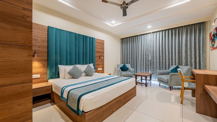 Spacious King size bed room with elegant design, writing desk, and seating area at Hotel Highway King, Bilaspur.