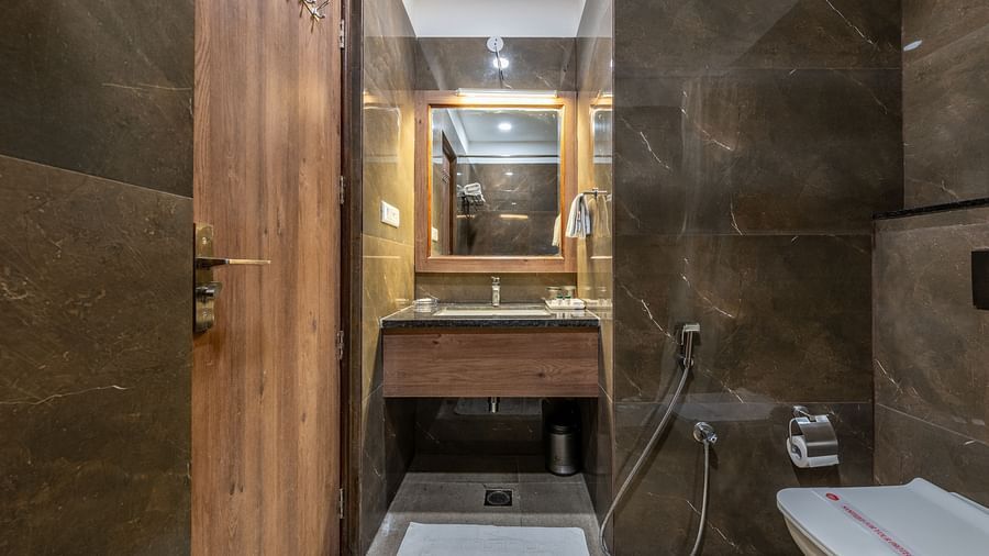 Contemporary bathroom with vanity, mirror, and shower enclosure at Hotel Highway King, Bilaspur.