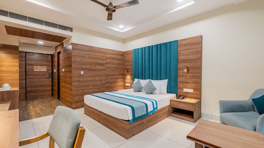 King size bed room with warm wooden tones, teal accents, and relaxed seating with a work station at Hotel Highway King, Bilaspur.