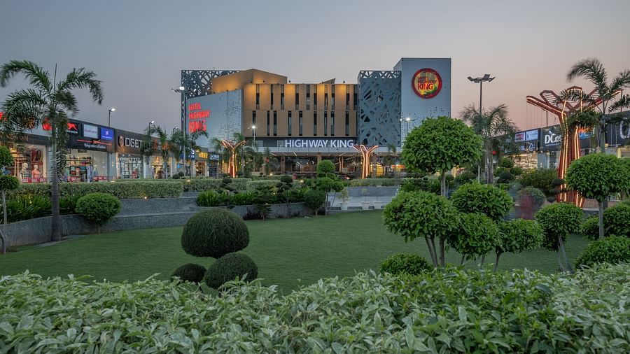 Lush landscaped lawn with exterior view of Hotel Highway King, Bilaspur during sunset.