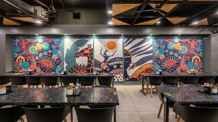 Colourful wall mural with vibrant artwork and neatly arranged tables at Hotel Highway King, Bilaspur.