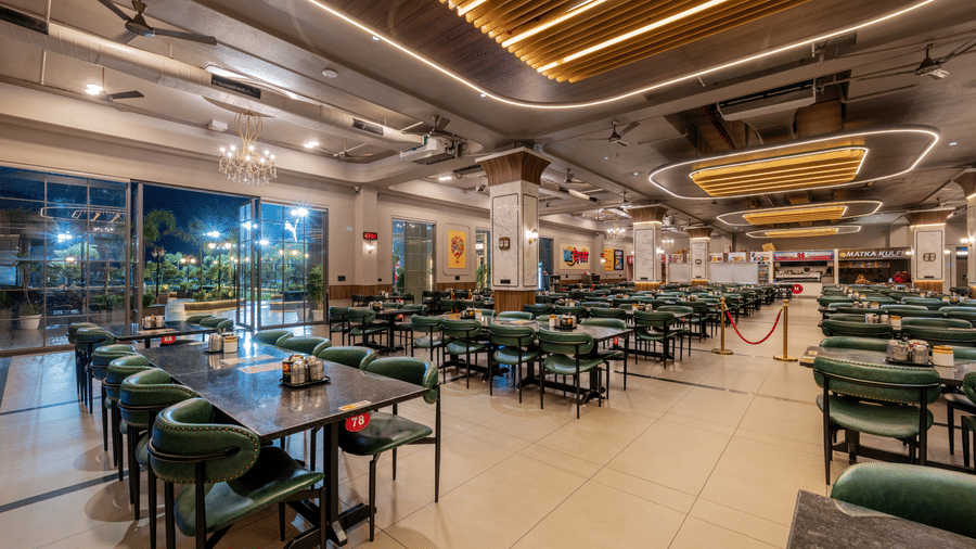 Corner view of the restaurant seating area next to floor-to-ceiling glass windows.