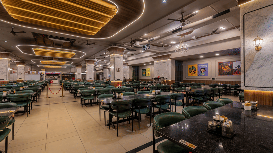 Spacious, well-lit restaurant dining hall with modern ceiling lighting and arranged dining tables.