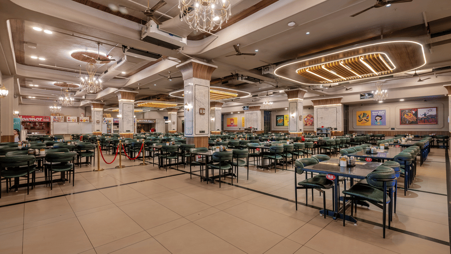 Open-plan restaurant dining space with large pillars, warm lighting, and numerous tables.