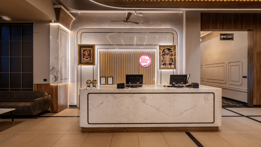 Reception area with a front desk, decorative wall panels, seating, and warm lighting.
