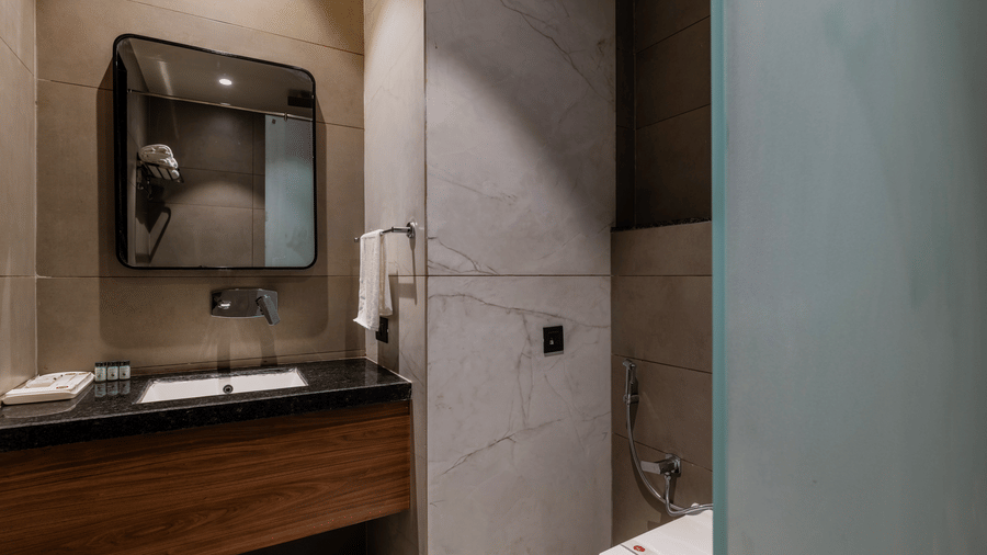 A washbasin with a mirror, a towel, and a toilet bowl at Hotel Highway King, Harmada.