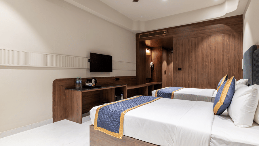 Hotel bedroom featuring double beds, a wooden desk unit, and a large wardrobe panel across the wall at Hotel Highway King, Harmada.