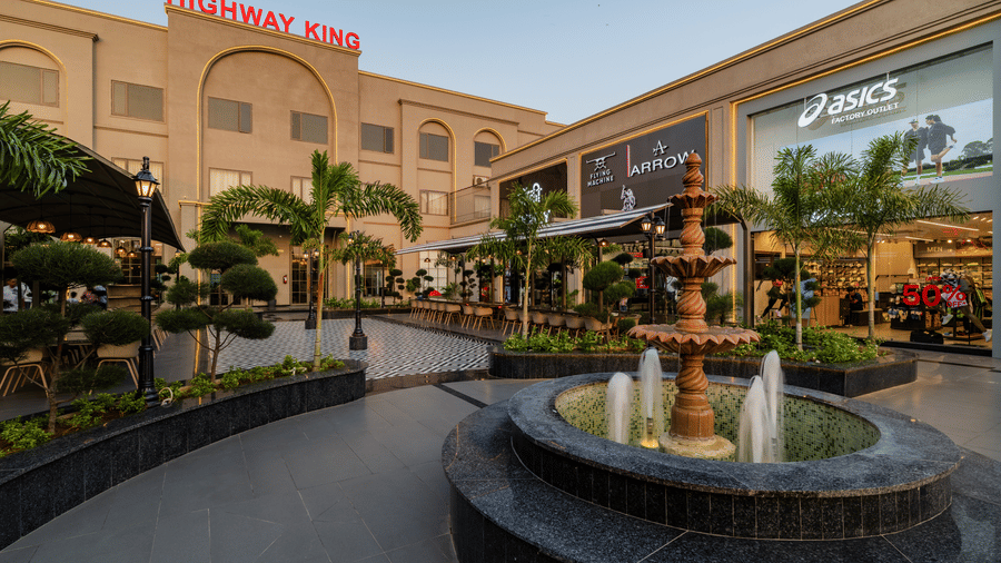 An operating water fountain, retail stores, and a hotel building at Hotel Highway King, Harmada.