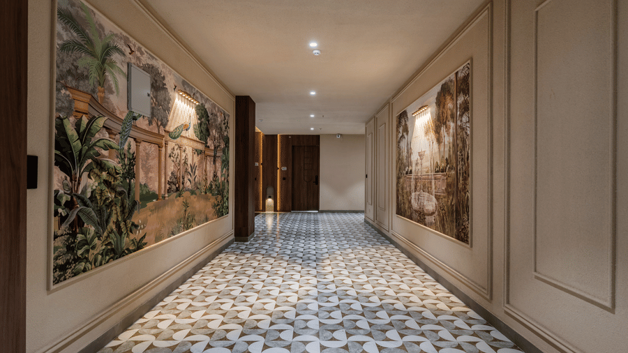 A spacious corridor with large traditional paintings on the walls, a decorative tiled floor, and a wooden pillar structure at Hotel Highway King, Harmada.