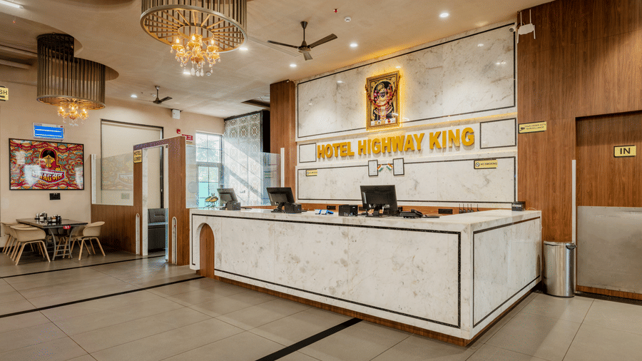 A reception area featuring a long marble counter, computer monitors, and a sign on the wall at Hotel Highway King, Harmada.