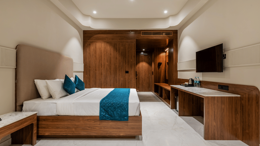 A king size bed, a television console, and wooden wall panelling at Hotel Highway King, Harmada.
