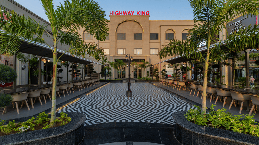 A view of an outdoor dining area with tables, chairs, and potted plants at Hotel Highway King, Harmada.