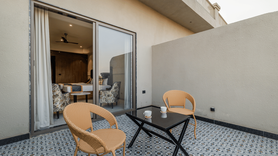 Outdoor balcony terrace with 2 wicker chairs, a small table, and a sliding glass door leading inside at Hotel Highway King, Harmada.