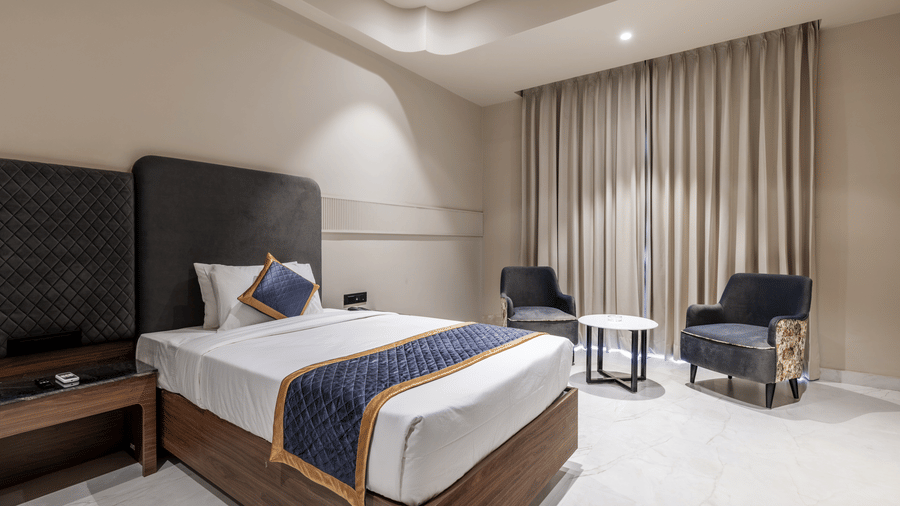 A single bed with a headboard, 2 armchairs, and a small round table at Hotel Highway King, Harmada.
