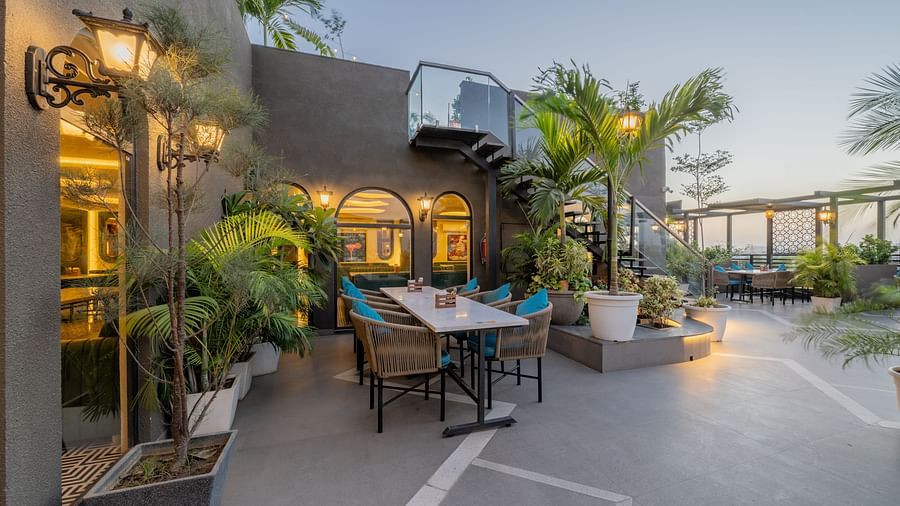 Cosy outdoor seating near arched window and tropical plants at Hotel Highway King, Jaipur.