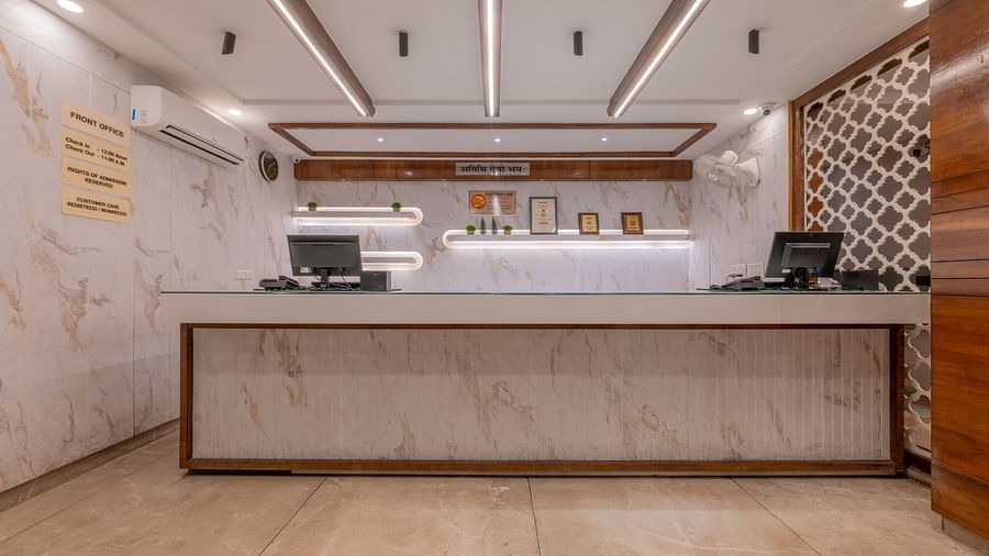 A reception desk with a marble counter and wall behind, featuring frames and lighting overhead at Hotel Highway King, Jaipur.