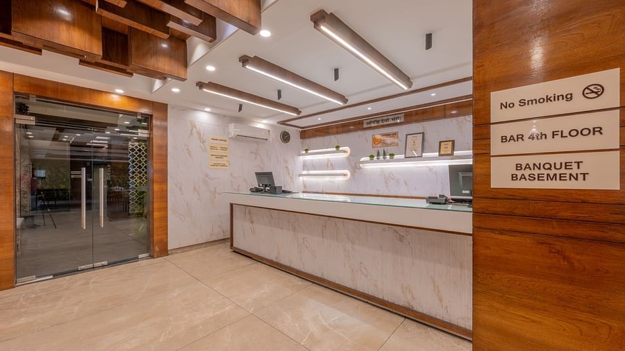 A reception area with a white marble desk and wooden ceiling design at Hotel Highway King, Jaipur.