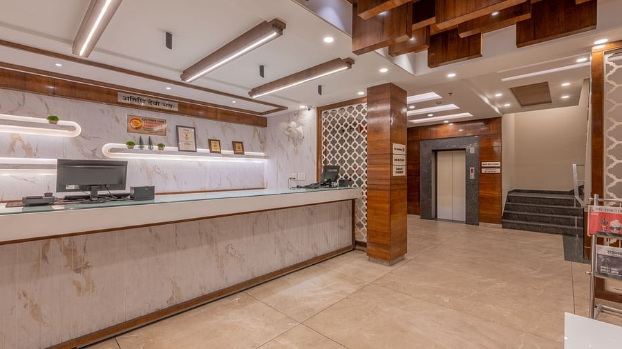 A view of the reception with white surfaces, wooden panels, and modern lighting at Hotel Highway King, Jaipur.
