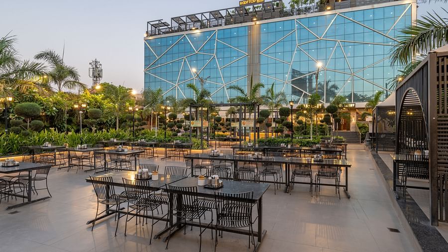 Outdoor dining tables and chairs set up on a patio with the facade of Hotel Highway King in the background.