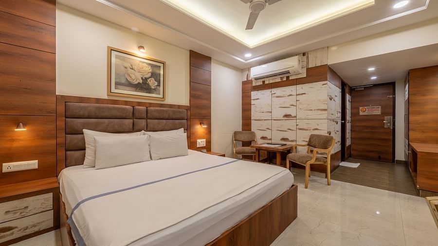 A bright room with a king size bed, a table with chairs and a wall art at Hotel Highway King, Jaipur.