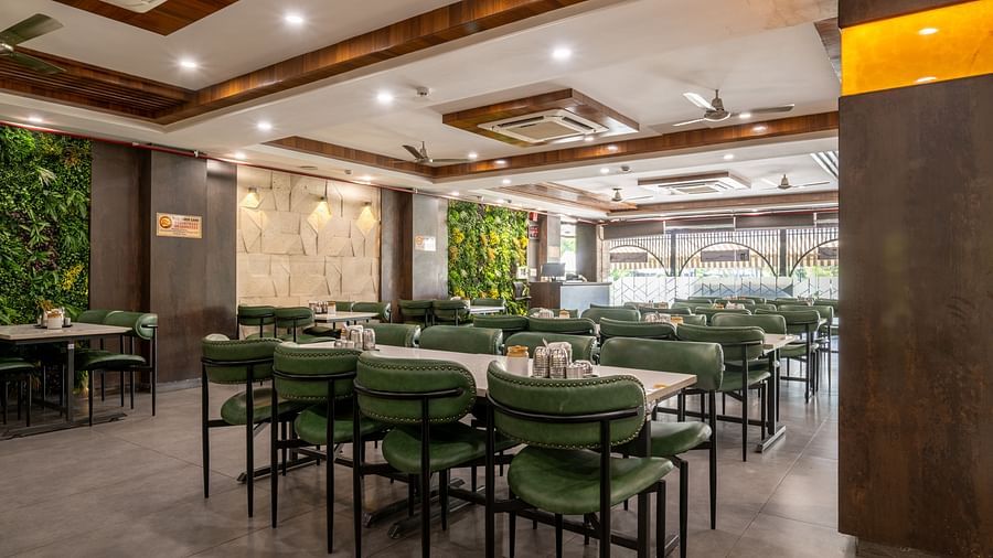 Indoor restaurant section with green chairs, vertical wall garden, and ceiling lights at Hotel Highway King, Jaipur.