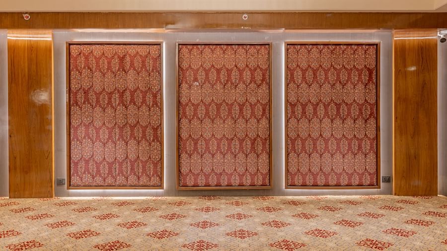 Closed banquet hall doors with patterned red panels and wooden framing on a carpeted floor at Hotel Highway King, Jaipur.