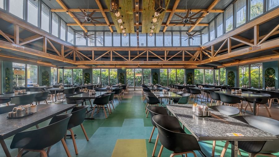 Dining space with colourful flooring, black chairs, and high glass windows at Hotel Highway King, Jaipur.