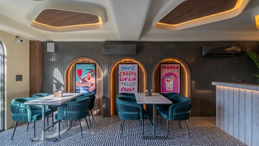 Indoor dining area with green chairs, wall arts, and tiled flooring at Hotel Highway King, Jaipur.
