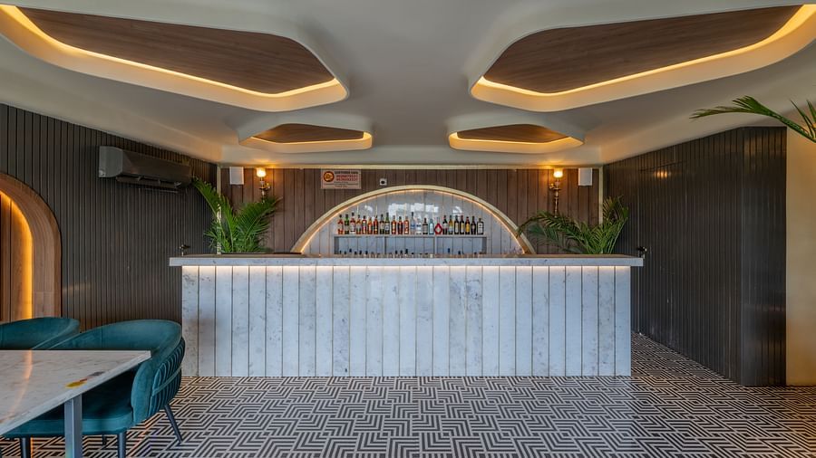 A bar reception with white panelling and drinks arranged in a curve counter under warm ceiling lights at Hotel Highway King, Jaipur.