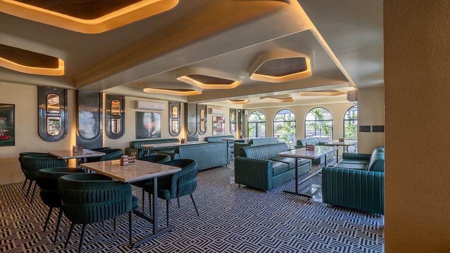 Indoor restaurant with green lounge chairs, framed wall art, and soft ceiling lighting at Hotel Highway King, Jaipur.