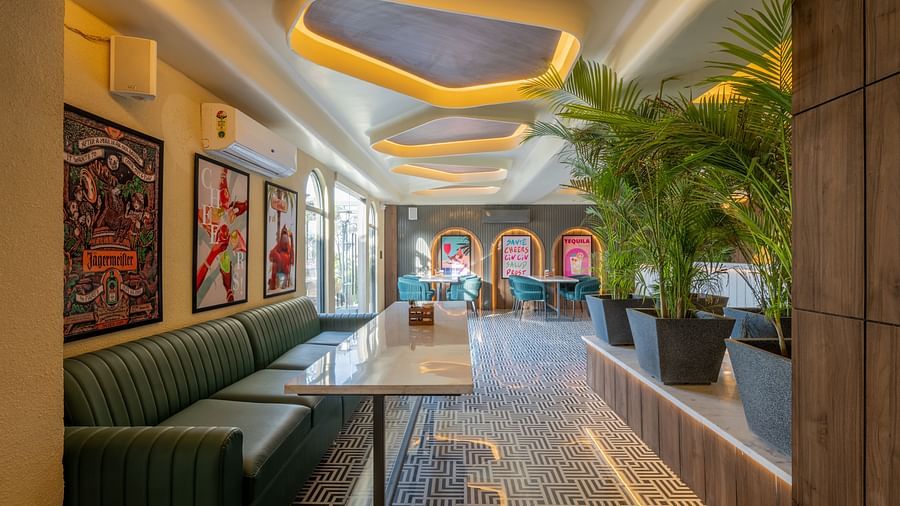 Cosy lounge corner with green seating, framed posters, plants, and ceiling lights at Hotel Highway King, Jaipur.