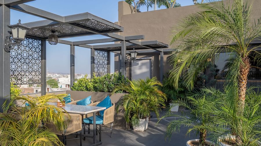 Terrace dining table surrounded by potted palms and city views at Hotel Highway King, Jaipur.