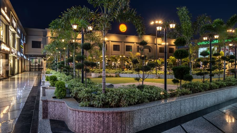 Walkway and landscaped garden at Hotel Highway King, Kishangarh with palm trees and night lighting.