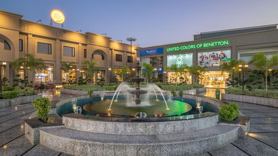 Evening view of fountain and courtyard at Hotel Highway King, Kishangarh with signage and building in the background.