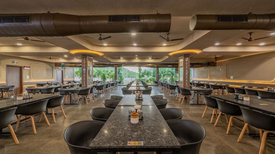 A spacious interior dining hall with modern table and chair settings at Hotel Highway King, Neelka.