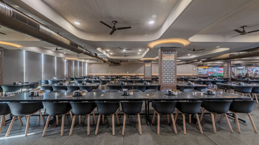 Chairs neatly arranged around a table, with blinds drawn, at Hotel Highway King, Neelka.
