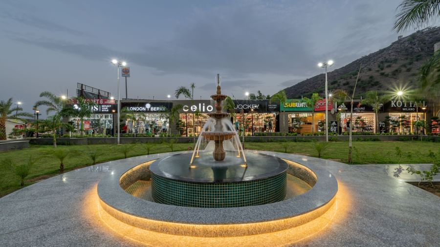 Close-up view of the fountain against the evening sky with a shopping complex in the background at Hotel Highway King, Neelka.