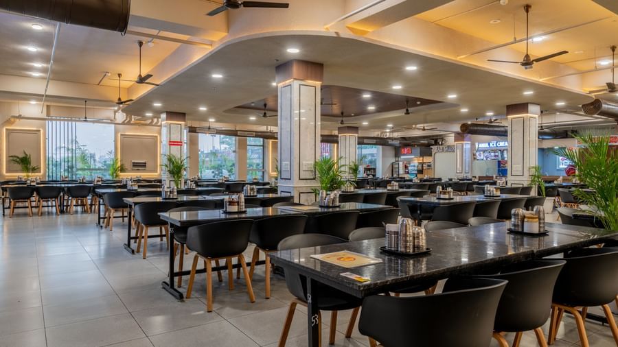 Spacious dining area with chairs arranged along polished tables and bright lighting at Hotel Highway King, Neemrana.