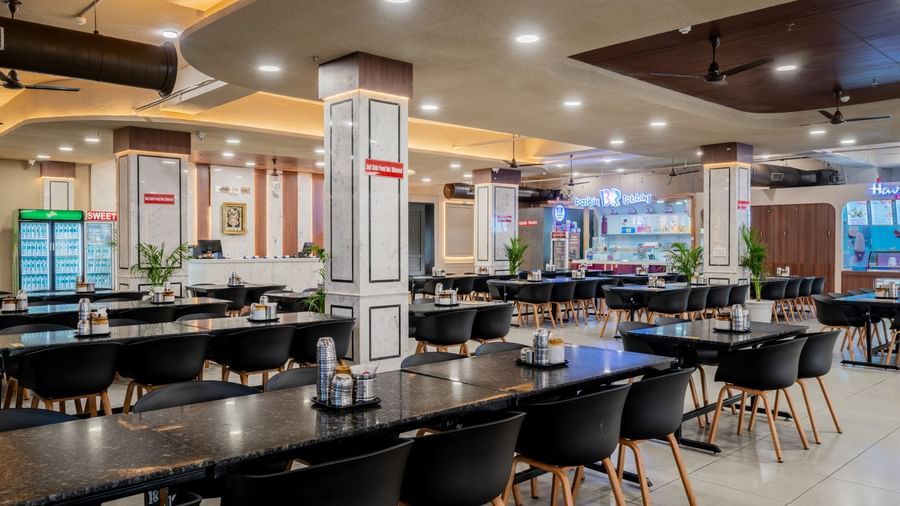Modern restaurant with neatly arranged seating and elegant ceiling lights at Hotel Highway King, Neemrana.
