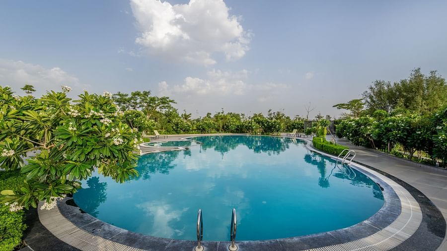 A panoramic view of the sparkling swimming pool at Hotel Highway King Shahpura under a clear sky.