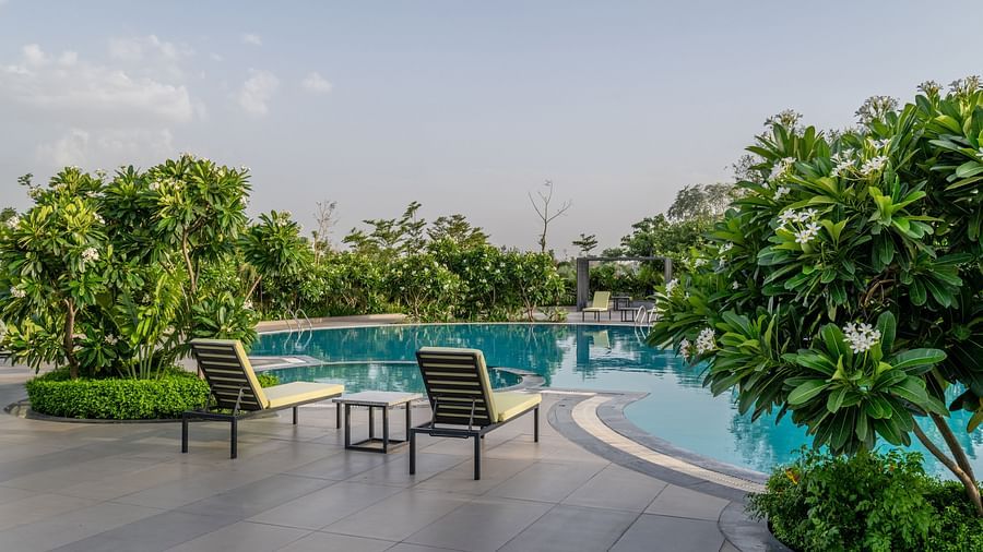 The inviting swimming pool area surrounded by lounge chairs and foliage at Hotel Highway King Shahpura.