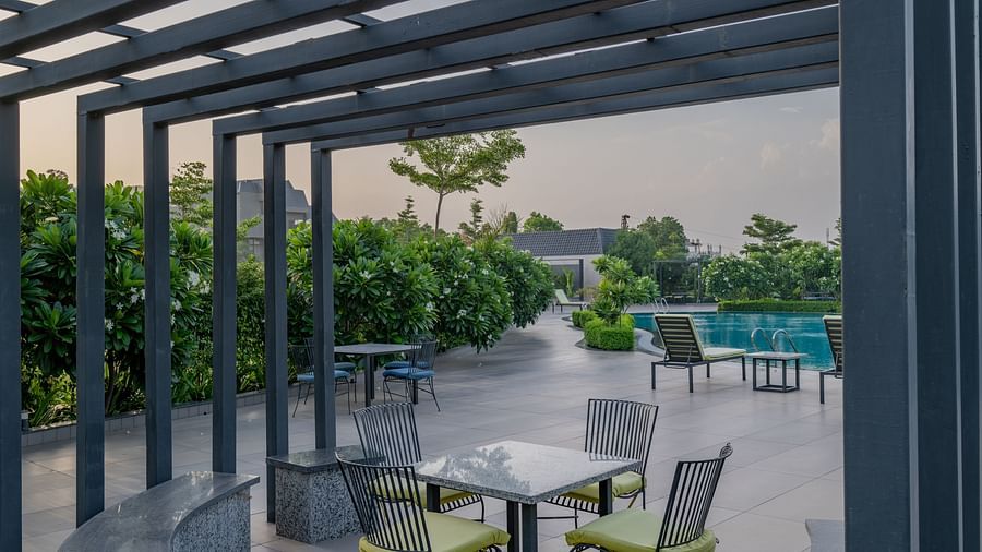The poolside deck with comfortable lounge chairs and greenery at Hotel Highway King Shahpura.