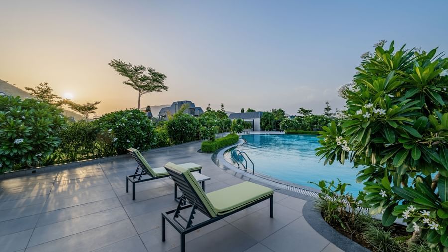 The serene swimming pool area with lounge chairs at Hotel Highway King Shahpura during dusk.