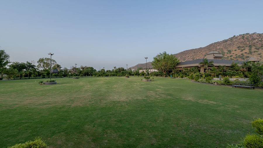 A large, well-maintained green lawn with distant hills at Hotel Highway King Shahpura.