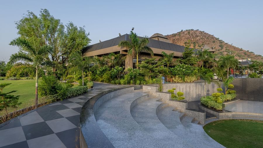 A serene view of the swimming pool with surrounding greenery and lounge chairs at Hotel Highway King Shahpura.